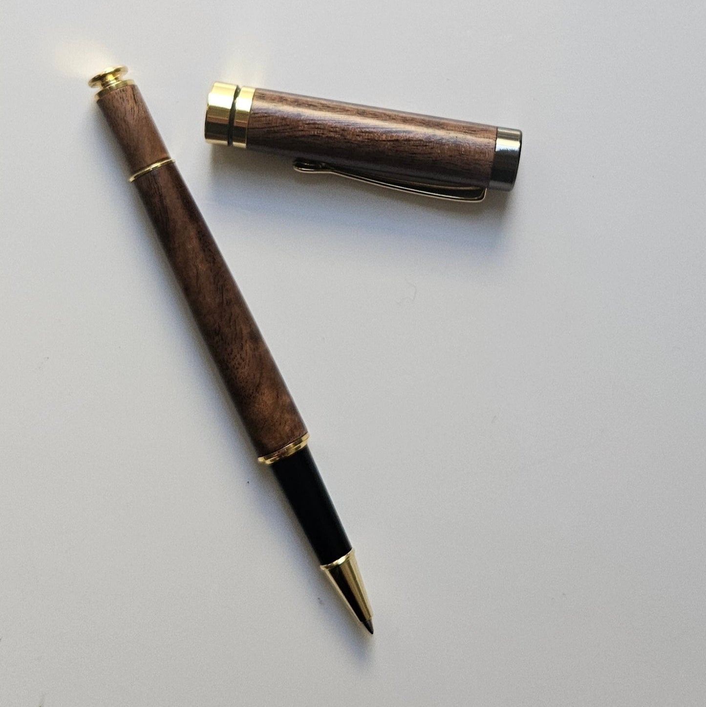 Luxury walnut wooden pen with gold accents on a light gray background