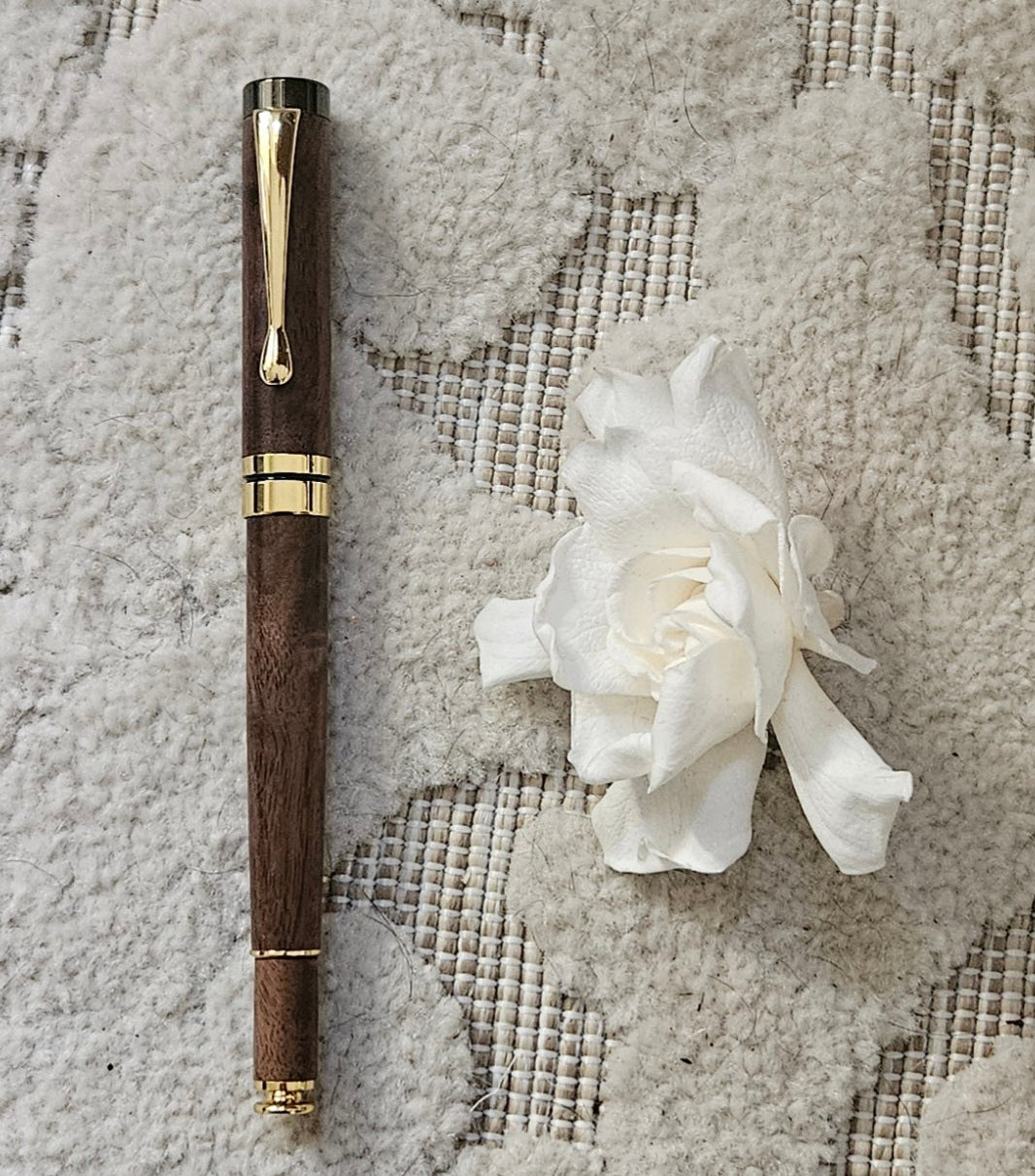 Luxury walnut pen and white flower on textured fabric background