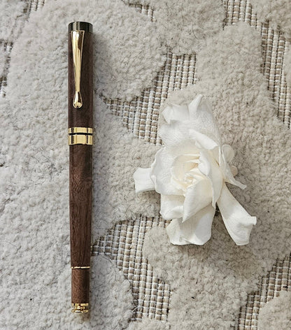 Luxury walnut pen and white flower on textured fabric background