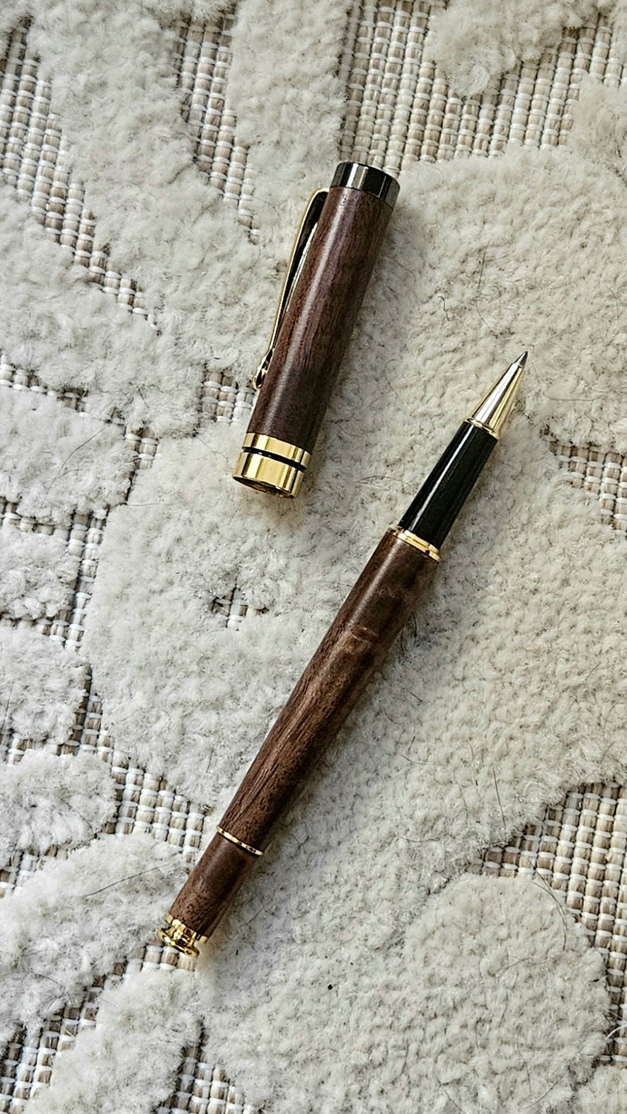 Luxury wooden walnut pen with gold accents on a textured surface