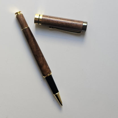 Luxury walnut wooden pen with gold accents on a light gray background